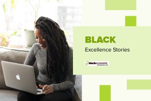 Black woman with locs looks at computer monitor while sitting on couch