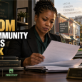 Black community lender reviews financing documents in an office overlooking neighborhood businesses, with the U.S. Treasury building in the distance.