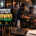 Black Memphis pitmaster tending barbecue ribs inside a multigenerational restaurant, with sauce bottles, shipping boxes and business documents representing ownership, distribution and succession.